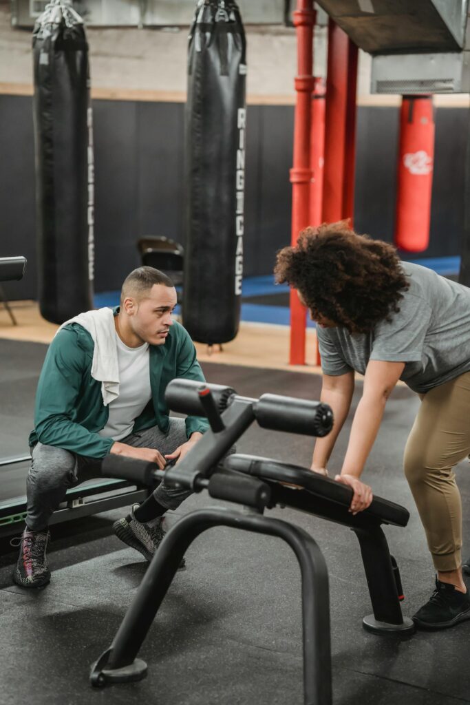 Personal trainer coaching cliente em academia com supervisão técnica