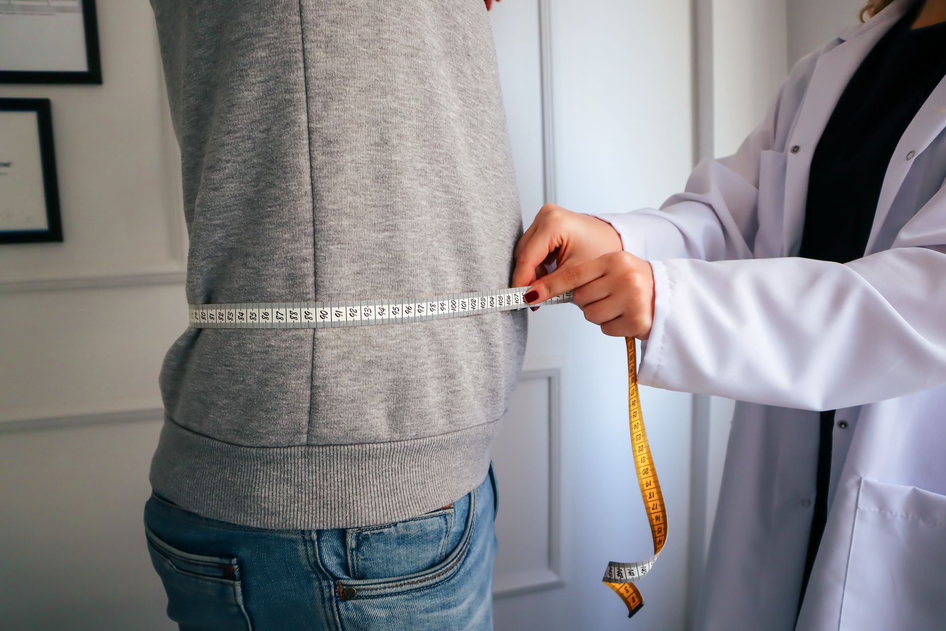 Profissional medindo circunferência de cintura com fita métrica em avaliação de composição corporal e massa magra